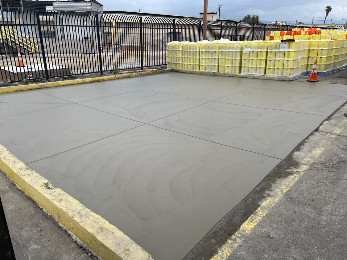 Newly poured concrete pad, floated and edged, kerbed with a yellow curb
