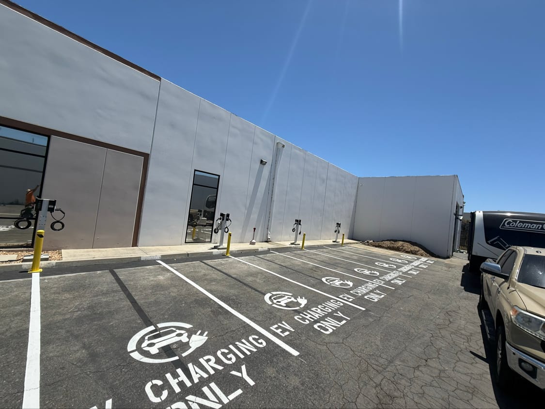 EV charging stalls with a painted charging-only legend and protective bollards