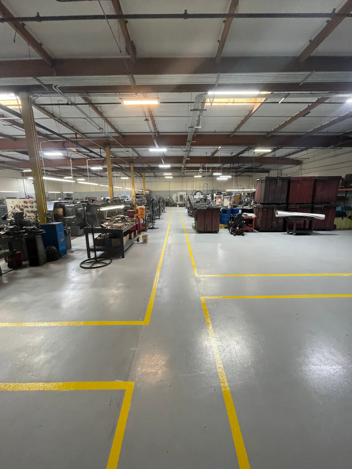 Warehouse floor with yellow aisle and rack markings around production equipment