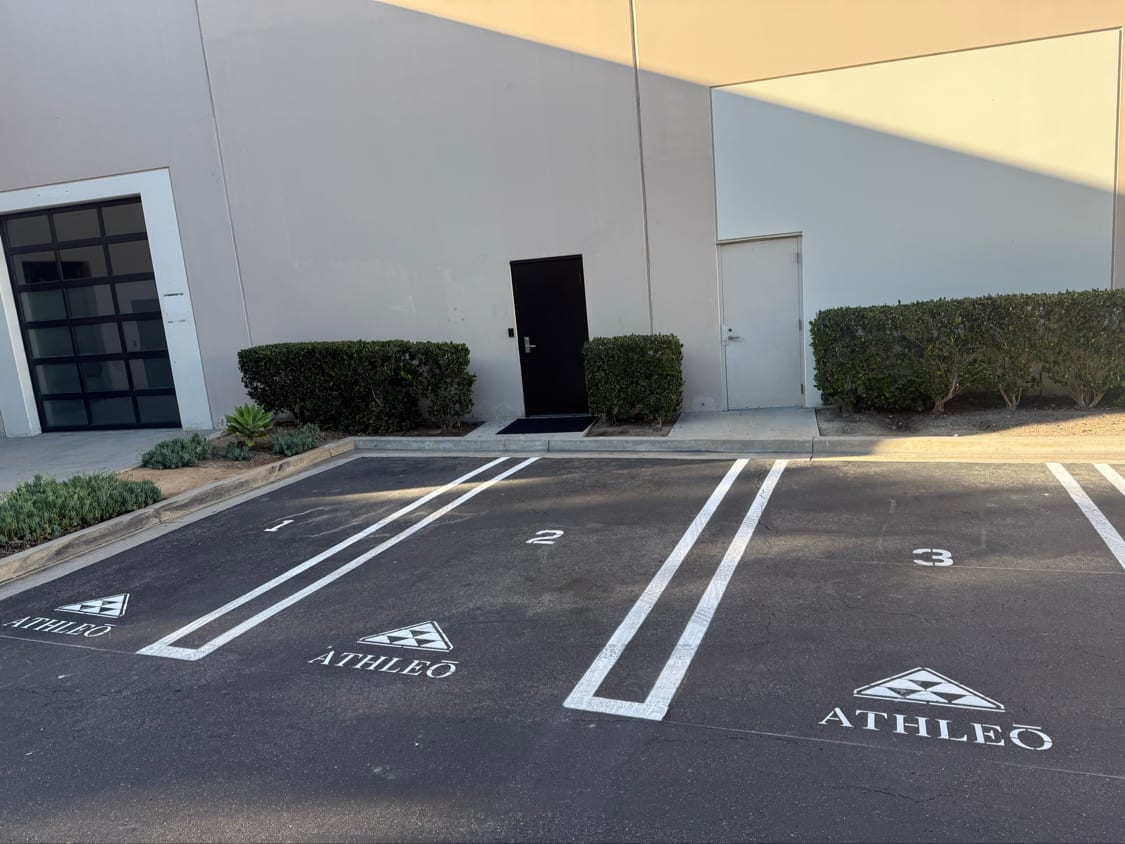 Numbered parking stalls with double white lines and a stencilled tenant name
